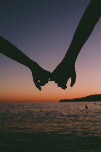 couple holding hands on beach at sunset