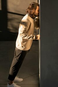 man with his forehead pressed against a wall looking defeated