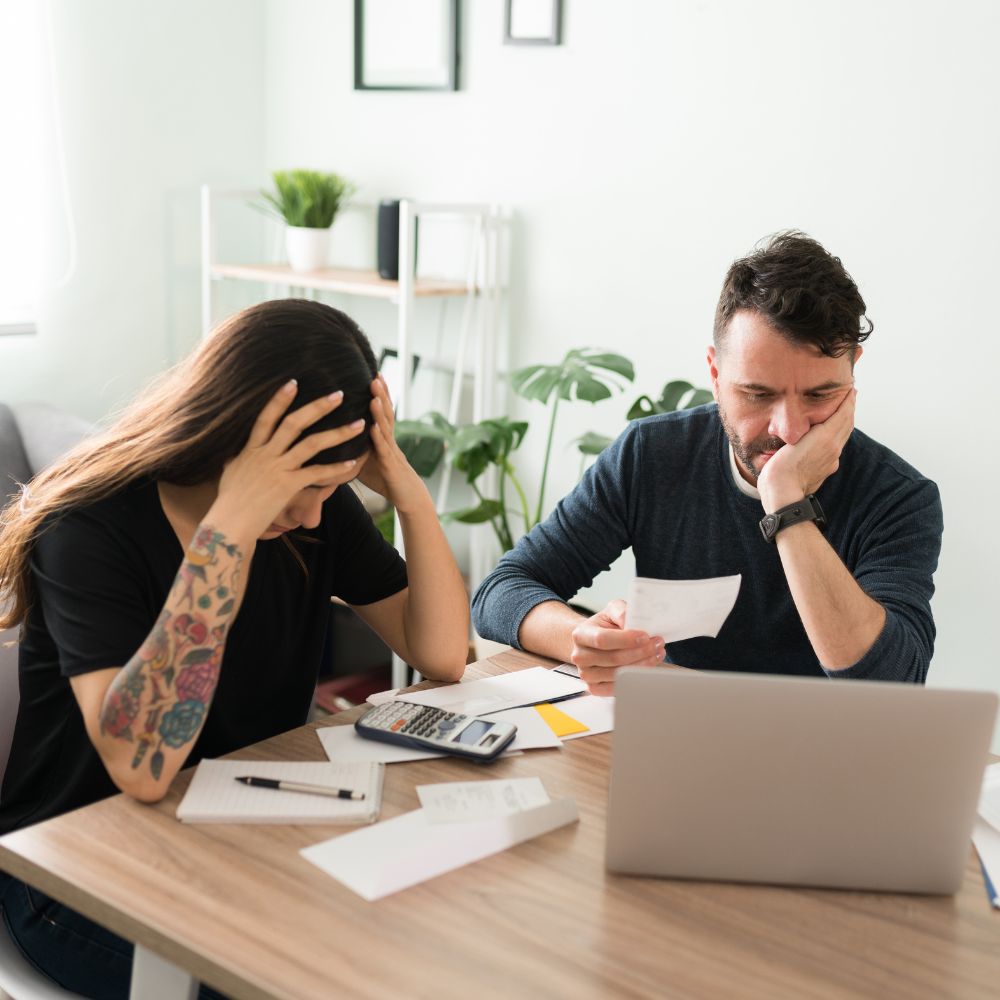 Stressed couple reviewing bills at dining table