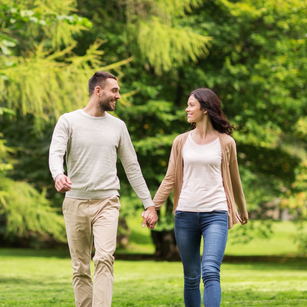 Happy couple holding hands walking in park
