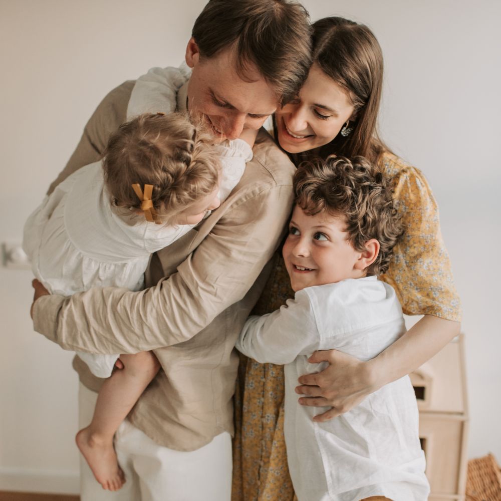 Smiling family hugging together in bright home