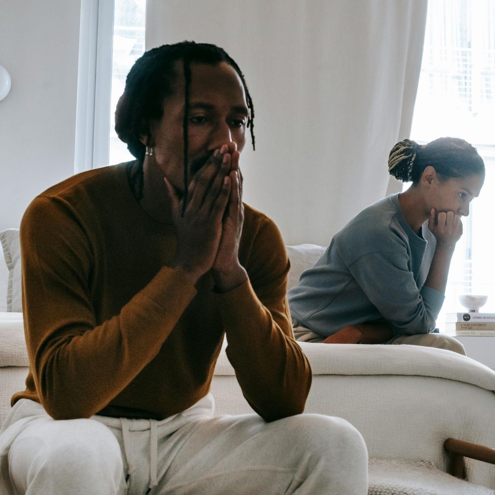 Couple sitting apart, both appearing deep in thought and distressed