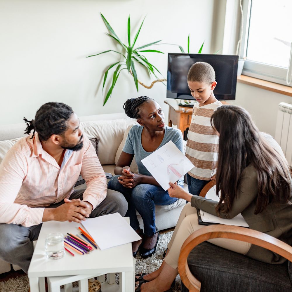 Parents and child talking with therapist reviewing child’s colorful drawing
