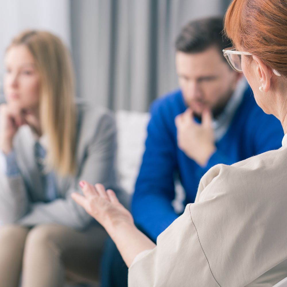 Therapist gesturing while couple listens silently during session