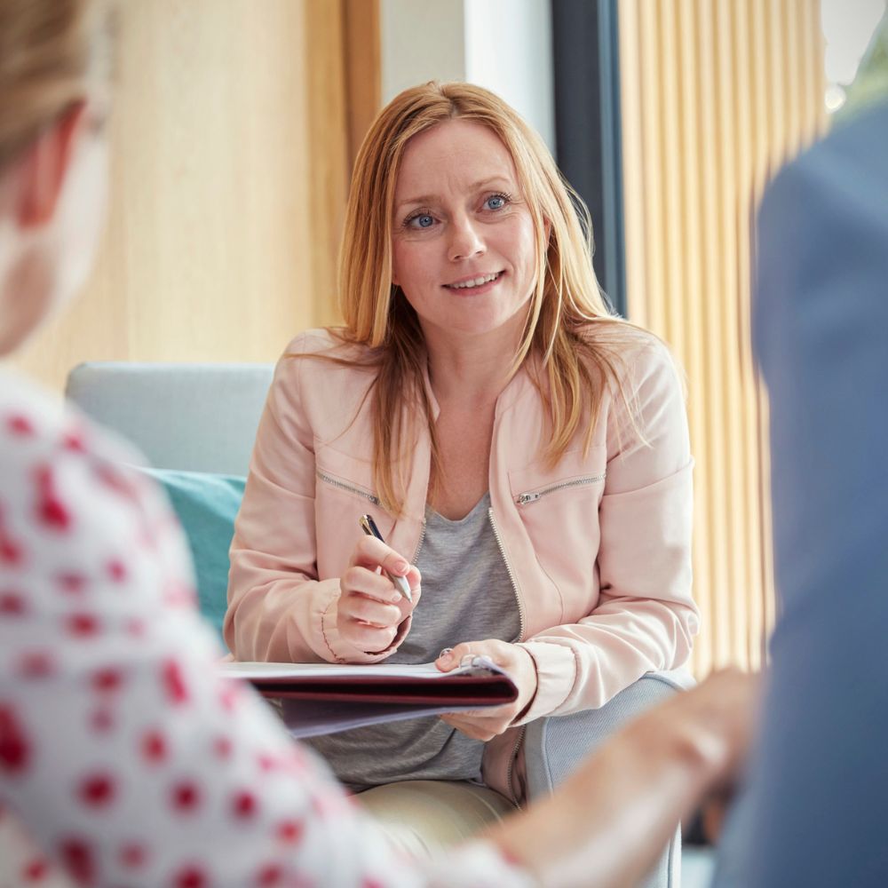 Smiling counselor listening to couple during supportive relationship session