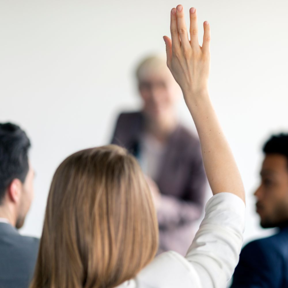 Woman raising hand to ask question during meeting