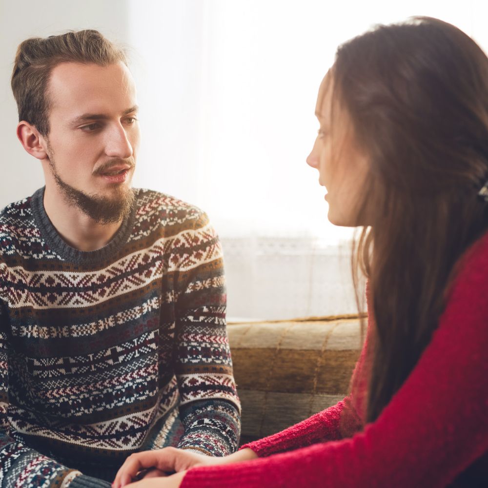 Couple talking seriously while sitting on living room couch