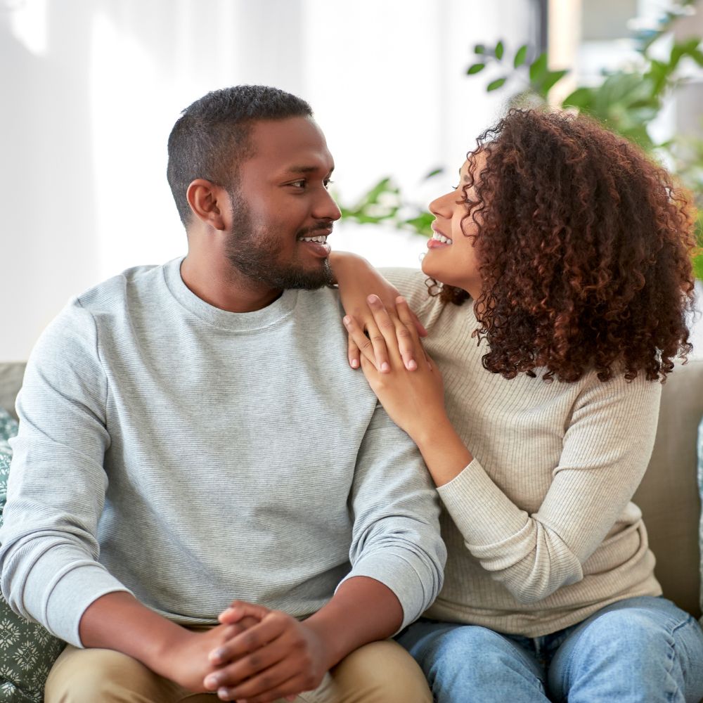 Smiling couple sitting closely together on living room couch