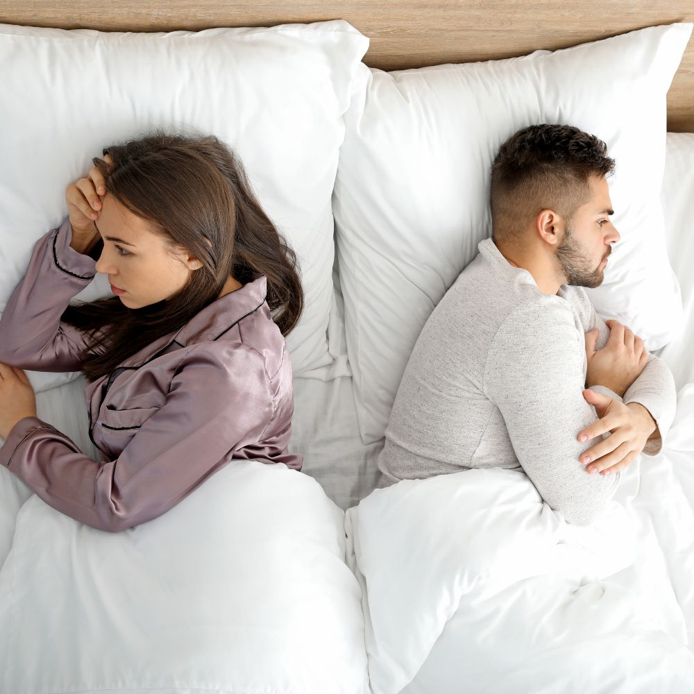Couple lying in bed turned away from each other