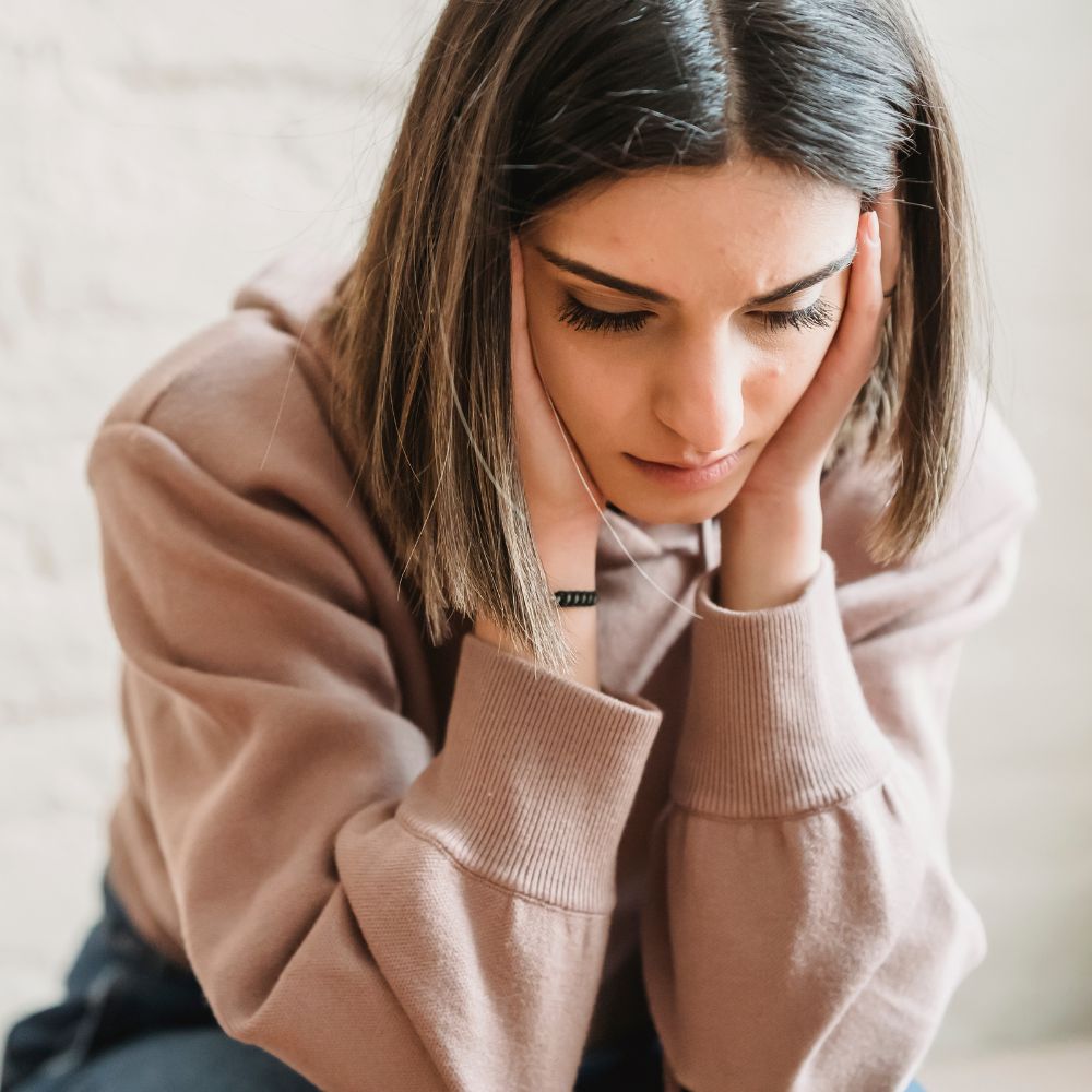 Young woman holding her head appearing overwhelmed and stressed
