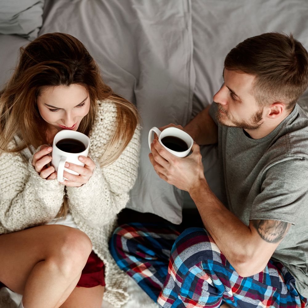 Couple in cozy pajamas sharing coffee and morning conversation in bed