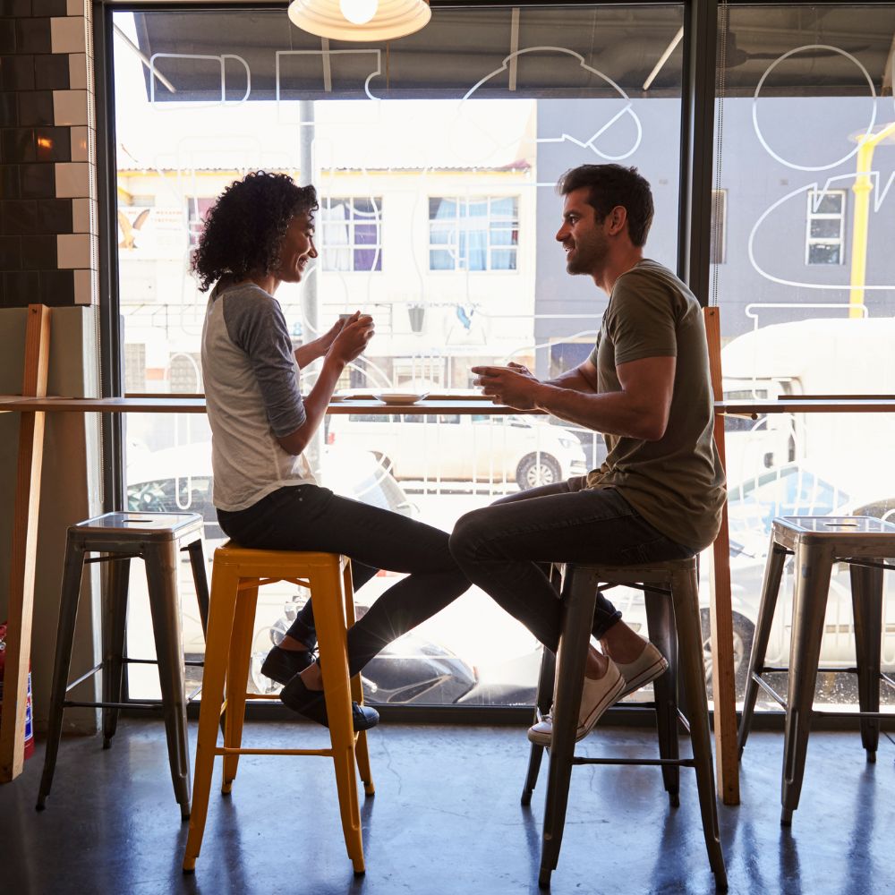 Couple laughing and chatting together at a cozy cafe table