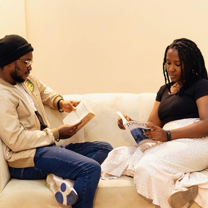 Couple sitting on a couch each reading a book
