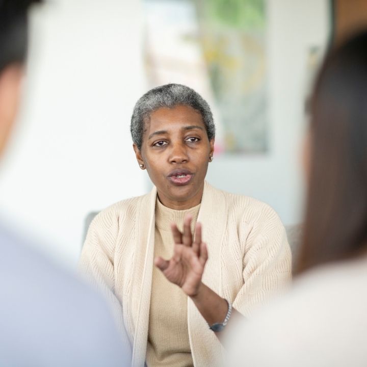 Female counselor speaking calmly using hand gestures while counseling a couple