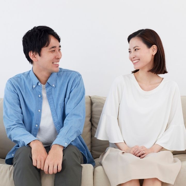 Smiling couple sitting on a couch, looking at each other warmly